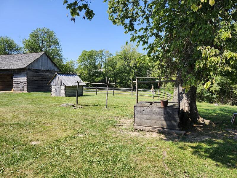 View out the door of the Lincoln cabin past the well and the large barn.