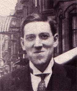 H.P. Lovecraft on the street with Victorian buildings and flags behind him.