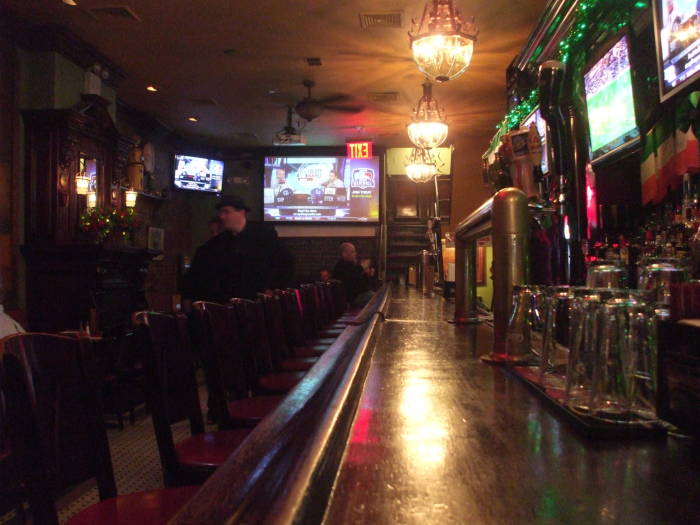 Interior of McGee's bar in New York, model for MacLaren's bar in 'How I Met Your Mother'.  Looking down the bar on the first floor: bar stools, booths at left, sports on flat-screen TVs, taps and glasses.