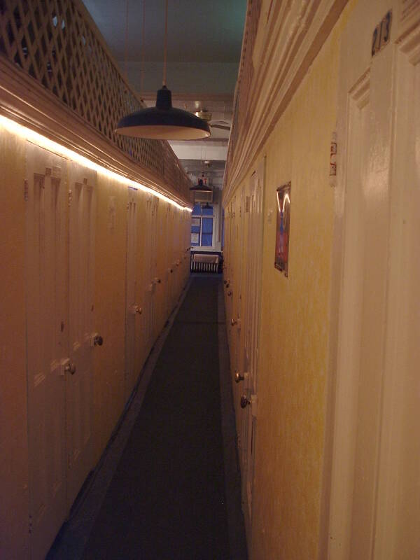 Hallway upstairs at the White House, yellow walls and narrow wooden doors, wooden lattice above, dim lighting.