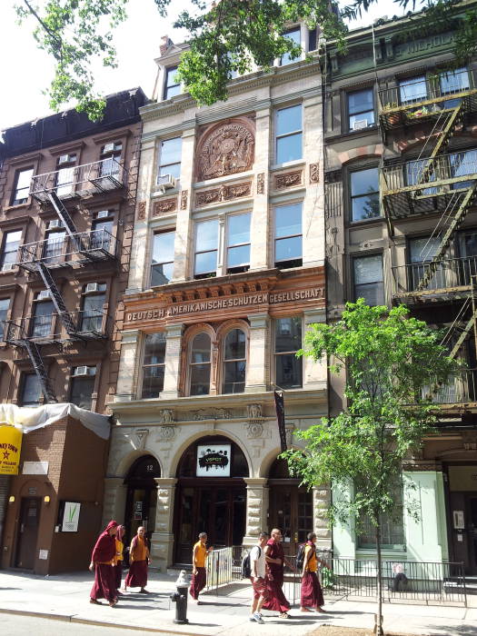 Buddhist monks walk in front of the German-American Shooting Society at #12 St. Marks Place between Third Avenue and Second Avenue in the East Village.