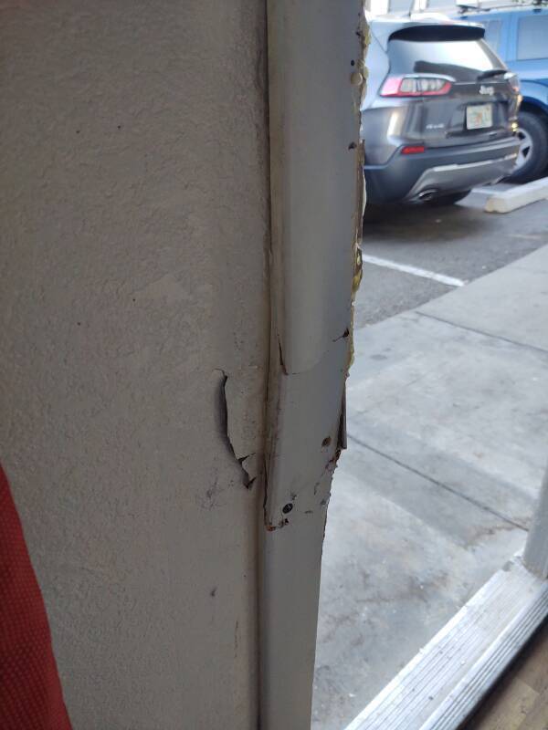 Motel 6 room door that has been forcibly opened with a battering ram.
