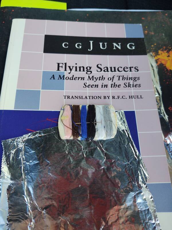 Jung's 'Flying Saucers' book holding aluminum foil and a sewing kit.