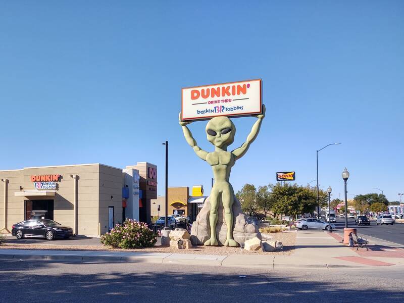 A tall alien statue holdes up the Dunkin' sign along North Main Street in Roswell, New Mexico