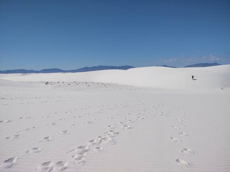 Man walking up a steep dune slope at White Sands.