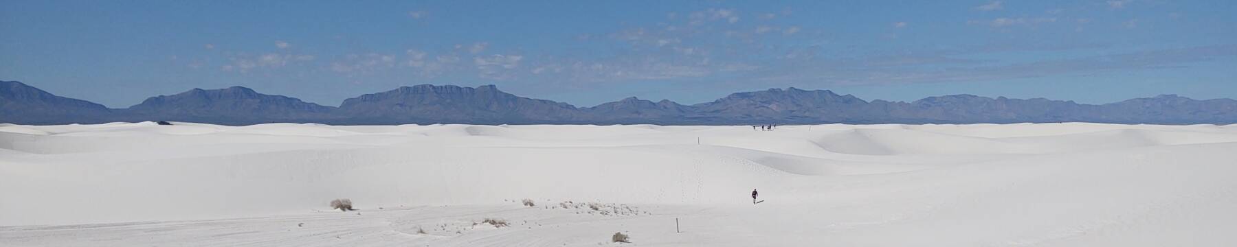 People in the distance on white gypsum dunes at White Sands National Park.