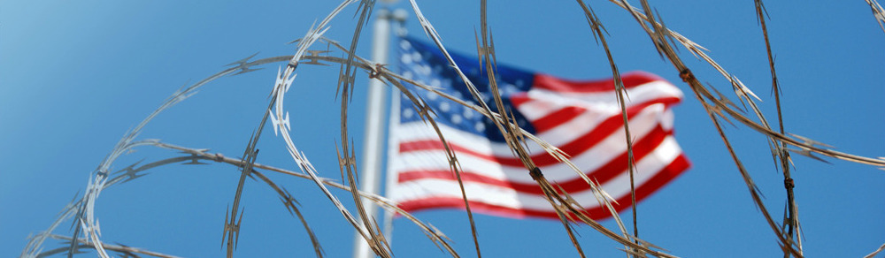 U.S. flag behind razor ribbon fencing.