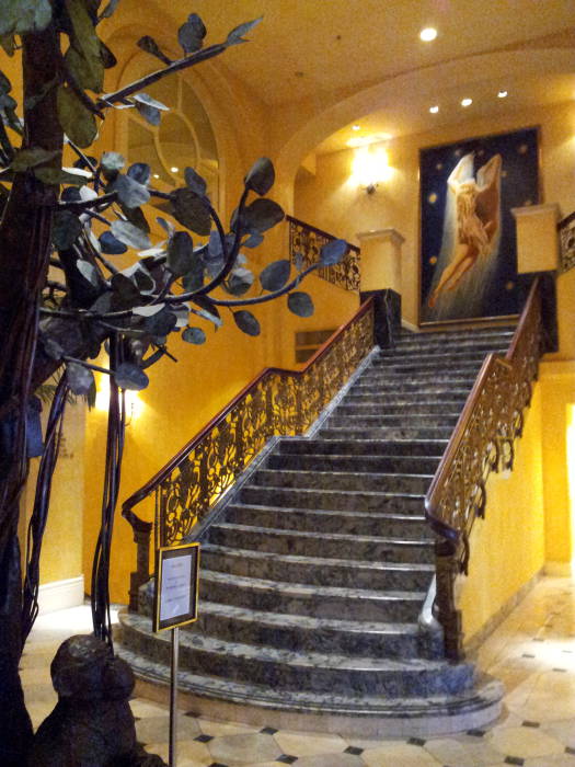 A marble staircase leads to a large painting on the landing in the Hotel Belvedere lobby.
