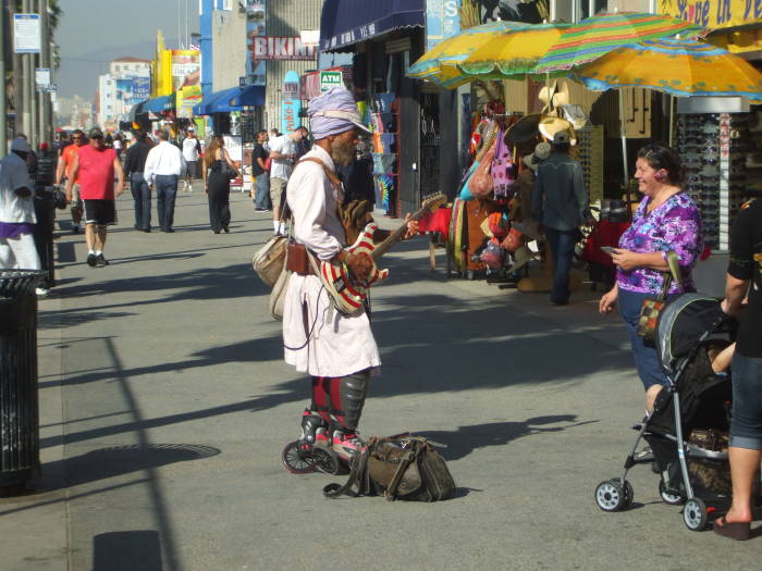 Harry Perry plays his electric guitar on roller skates on the boardwalk in Venice, California.